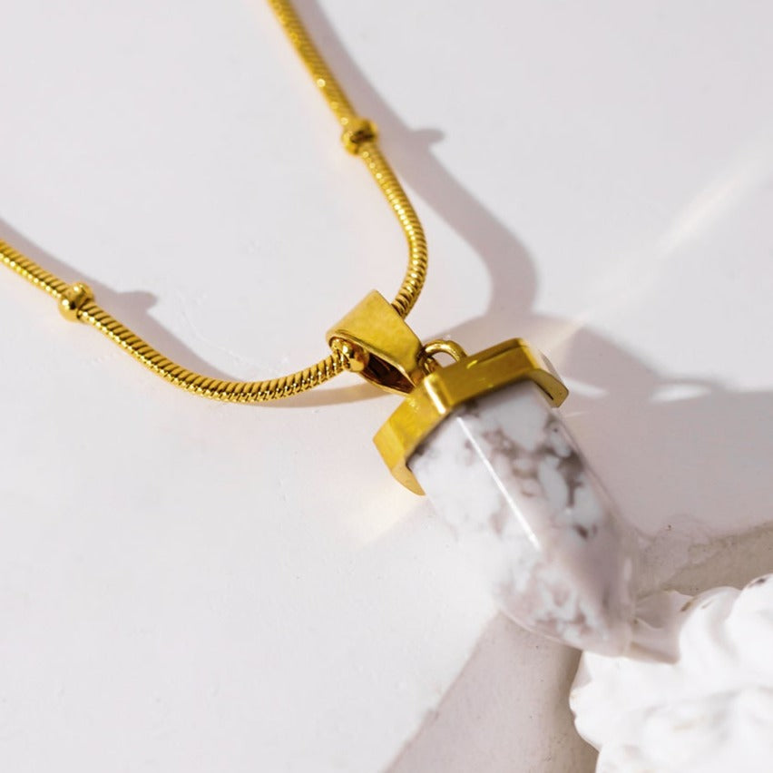 AMELIE : Collier avec pendentif en pierre turquoise blanche, accroché à une chaîne perlée texturée imitant la peau de serpent.