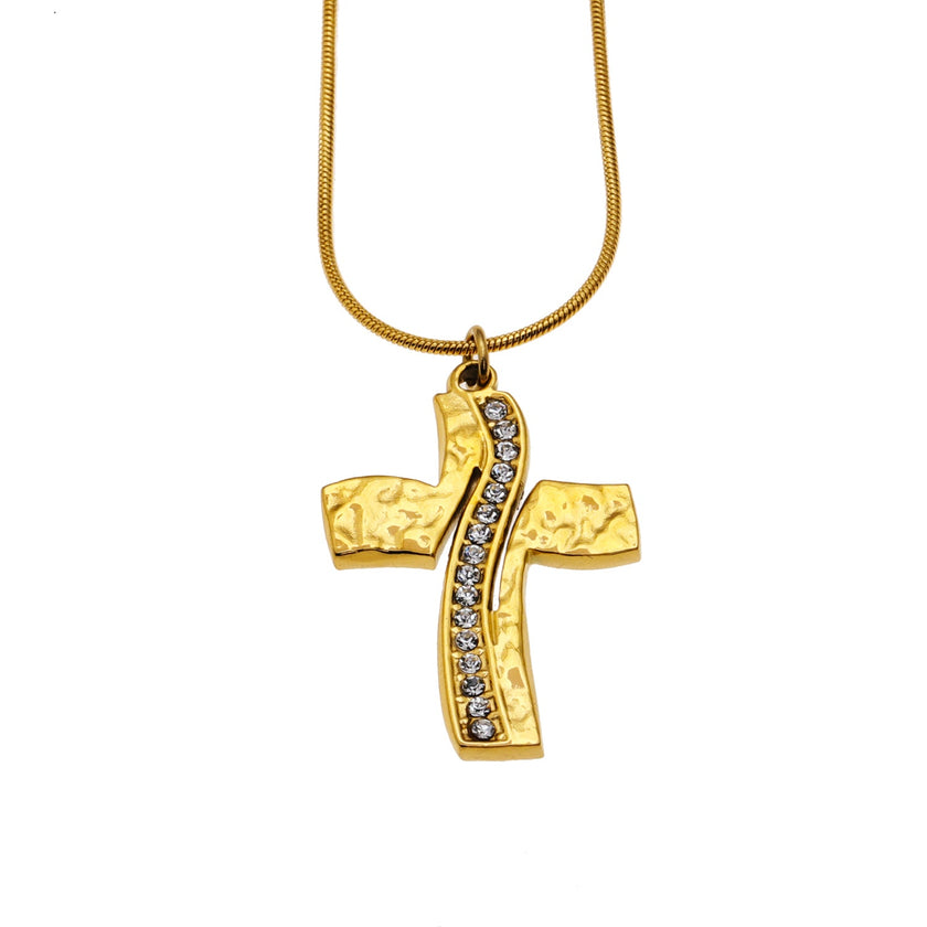 ARCASSA : Pendentif croix en zircone incrusté avec finition martelée, porté sur un mini collier à chaîne texturée imitation peau de serpent.