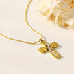 ARCASSA : Pendentif croix en zircone incrusté avec finition martelée, porté sur un mini collier à chaîne texturée imitation peau de serpent.