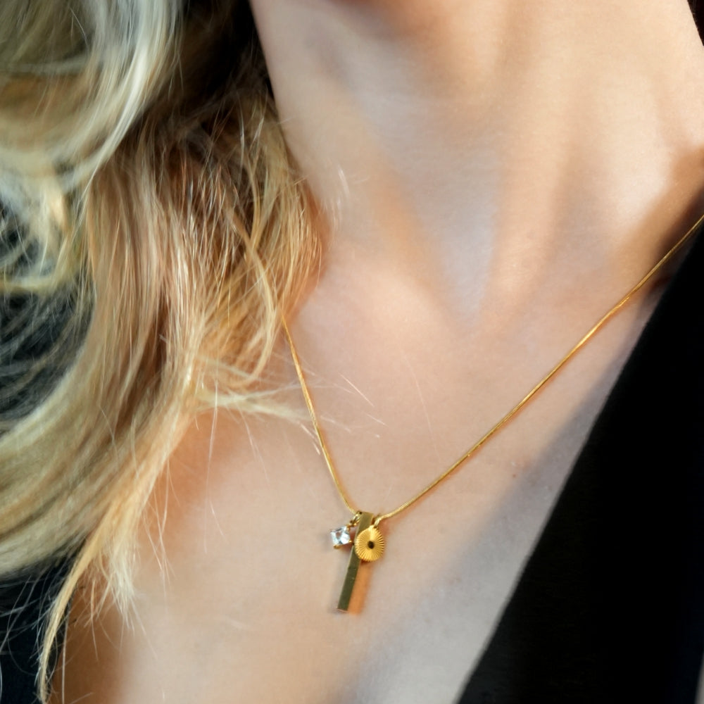 Style DEFNIE : Collier délicat à chaîne texturée effet peau de serpent, agrémenté d'un trio de breloques.