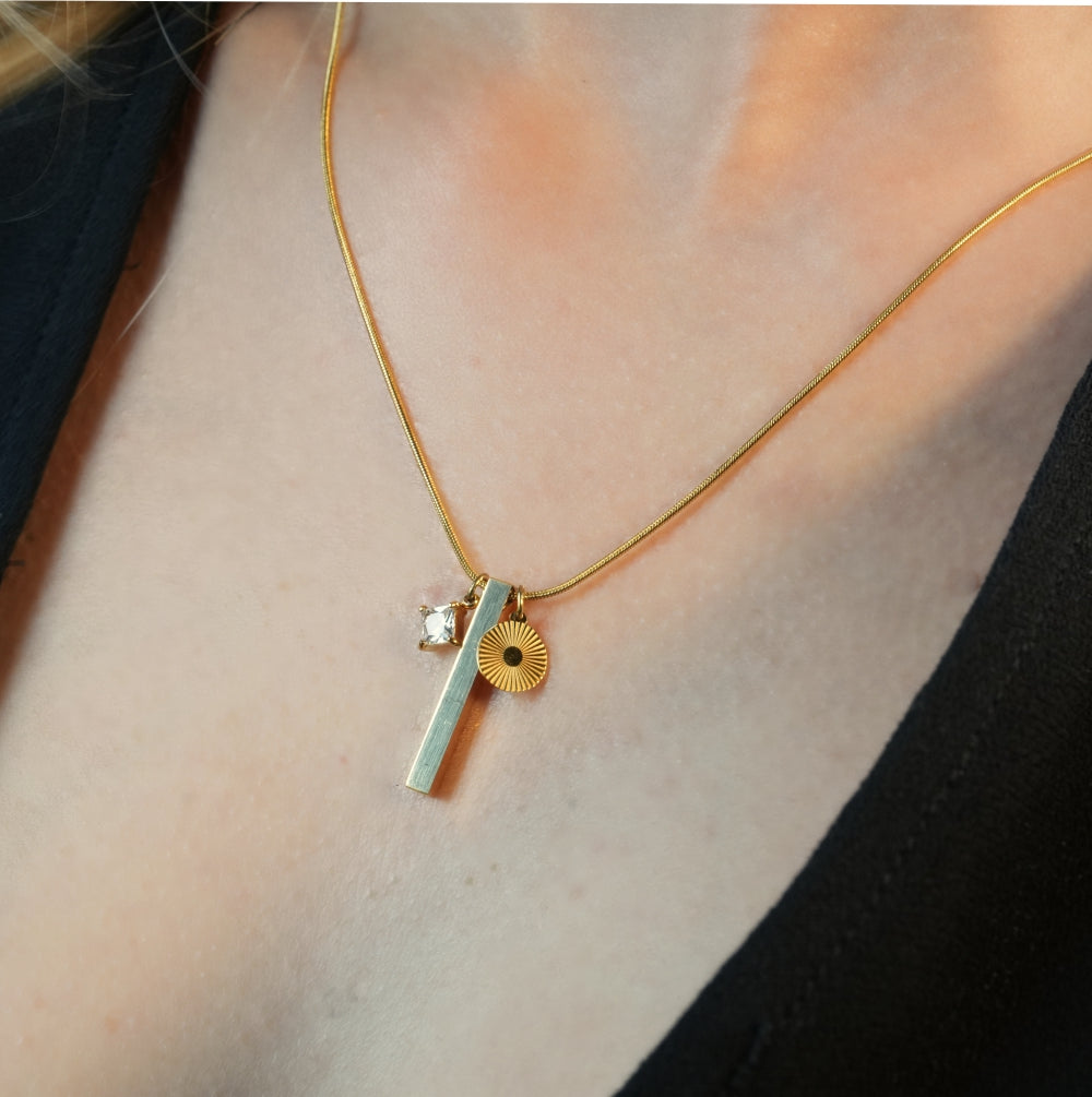 Style DEFNIE : Collier délicat à chaîne texturée effet peau de serpent, agrémenté d'un trio de breloques.