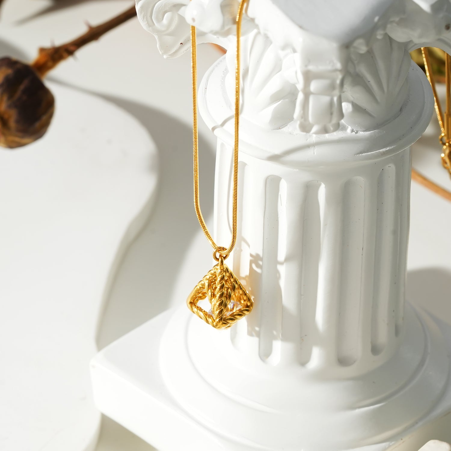 Style KARJAT : Collier à chaîne dorée avec pendentif en zircone géométrique en cage.