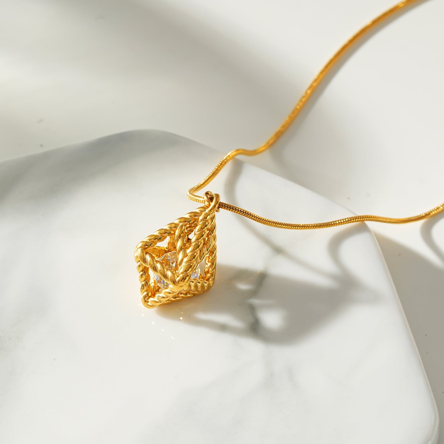 Style KARJAT : Collier à chaîne dorée avec pendentif en zircone géométrique en cage.