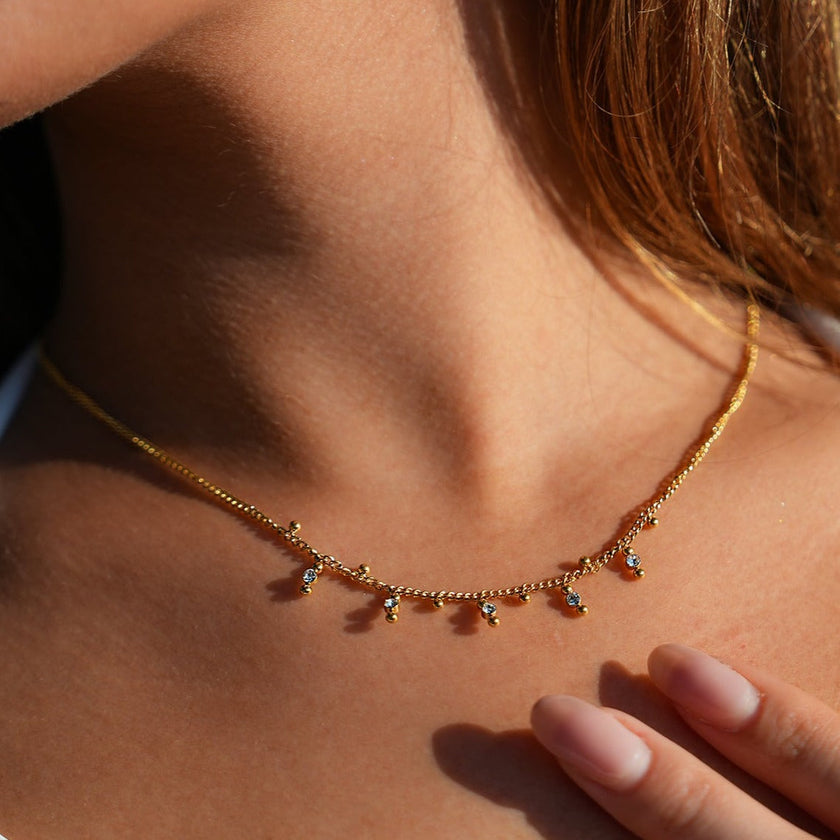 Style KALPI : Collier en chaîne à perles et zircons dorés.