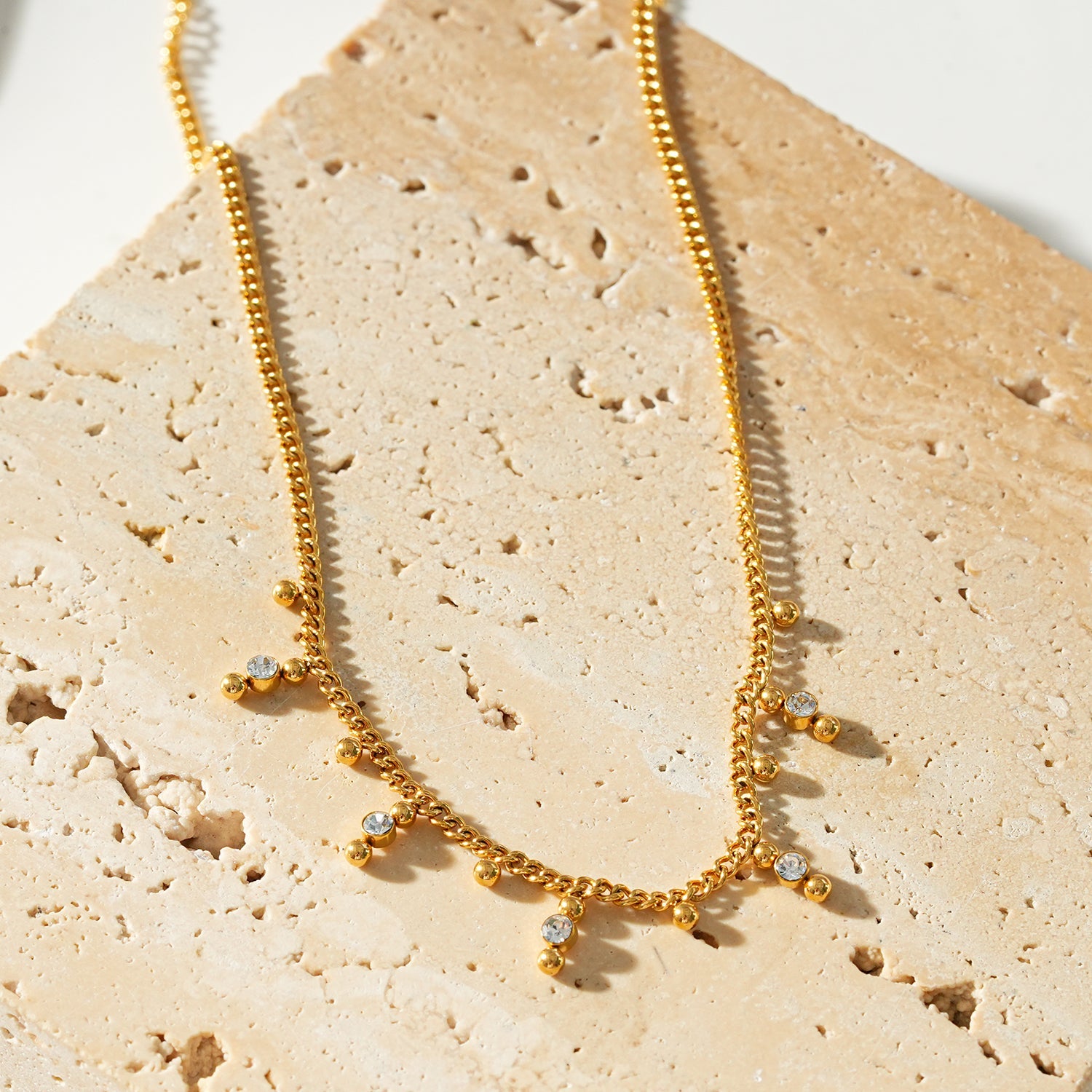 Style KALPI : Collier en chaîne à perles et zircons dorés.