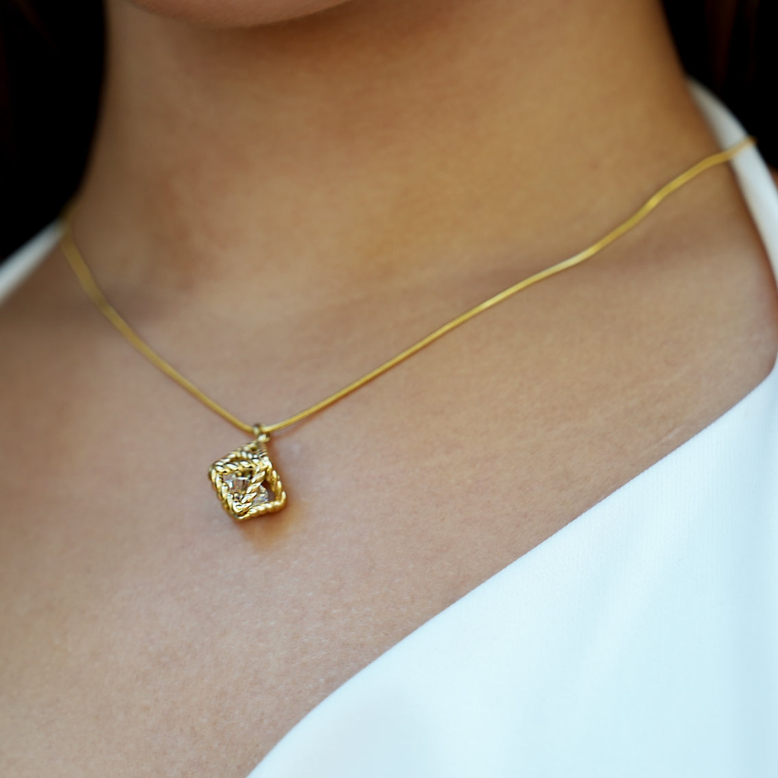 Style KARJAT : Collier à chaîne dorée avec pendentif en zircone géométrique en cage.