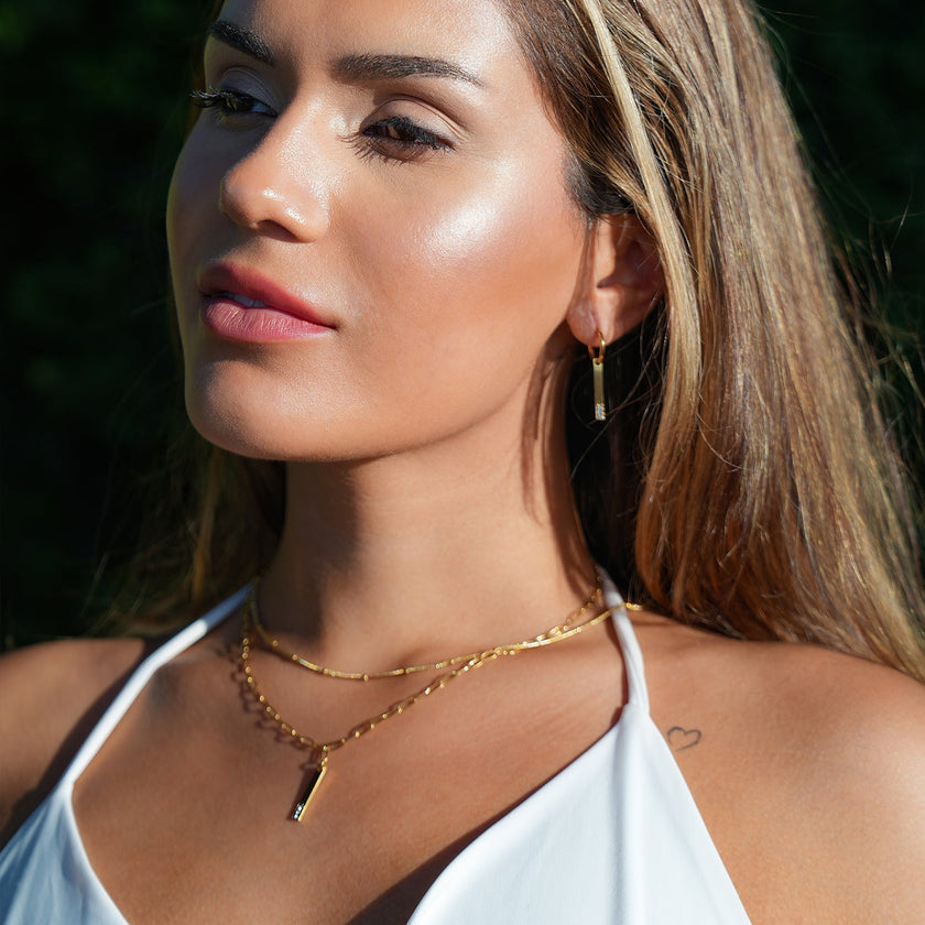 Style KORATIA : Collier minimaliste avec chaîne à maillons plats et pendentif barre en or incrusté de zircone.