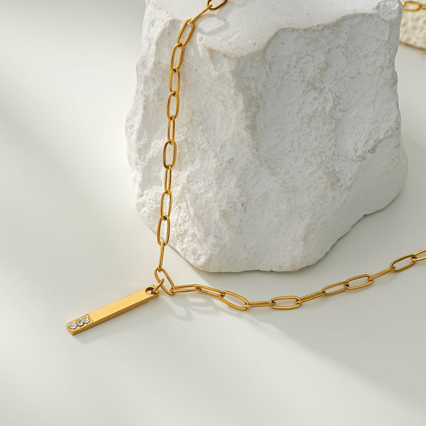 Style KORATIA : Collier minimaliste avec chaîne à maillons plats et pendentif barre en or incrusté de zircone.