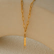 Style KORATIA : Collier minimaliste avec chaîne à maillons plats et pendentif barre en or incrusté de zircone.