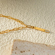 Style KORATIA : Collier minimaliste avec chaîne à maillons plats et pendentif barre en or incrusté de zircone.
