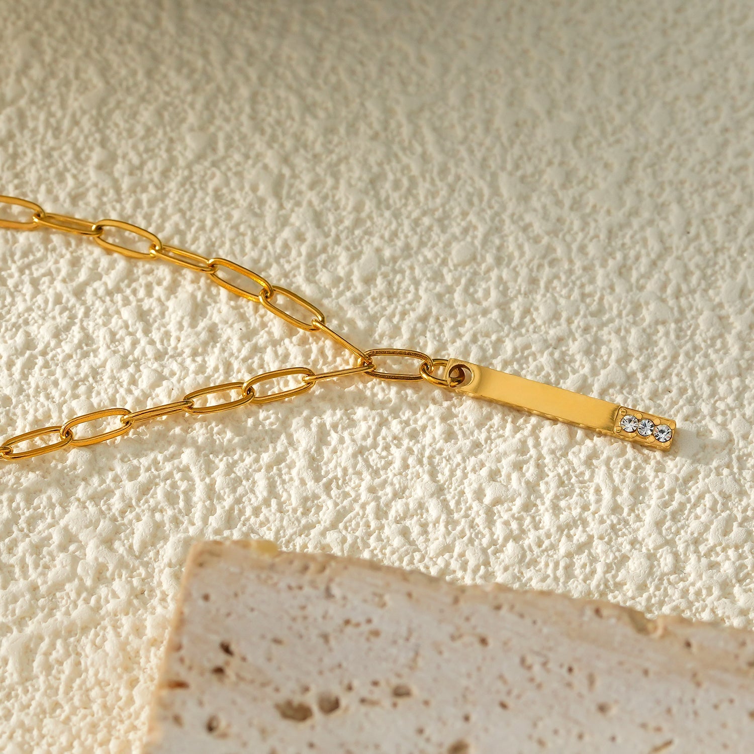 Style KORATIA : Collier minimaliste avec chaîne à maillons plats et pendentif barre en or incrusté de zircone.