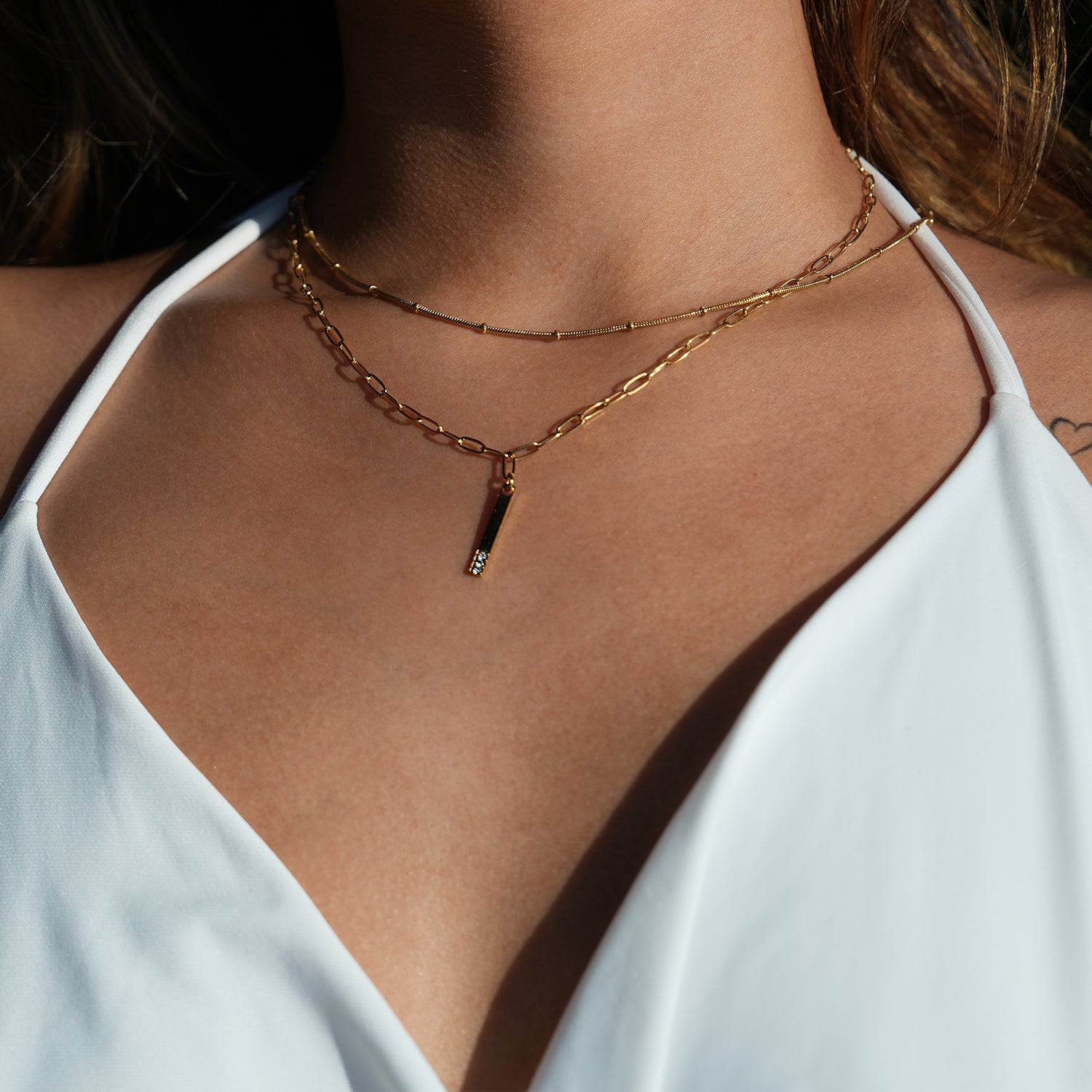 Style KORATIA : Collier minimaliste avec chaîne à maillons plats et pendentif barre en or incrusté de zircone.