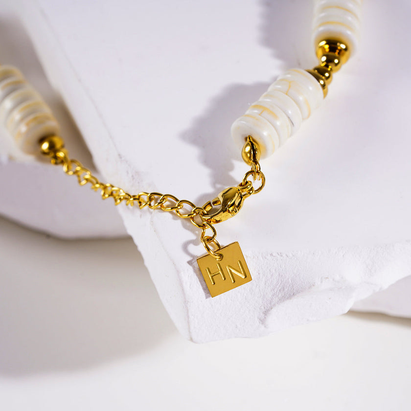 LULAMA : Collier bohème moderne en chaîne avec pierres de turquoise blanche et perles dorées.