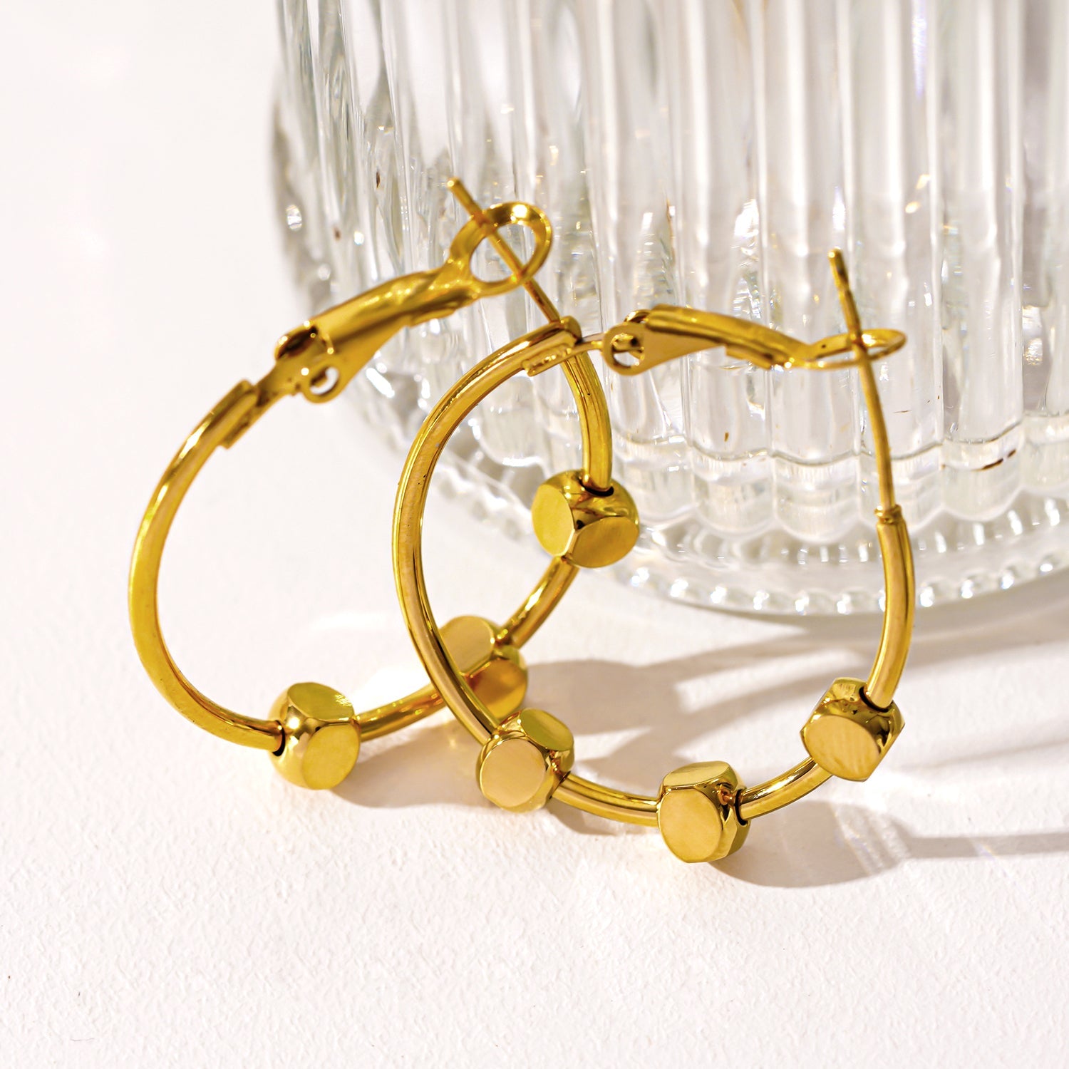MASUYO : Boucles d'oreilles rondes avant-gardistes rehaussées d'un trio de perles carrées.