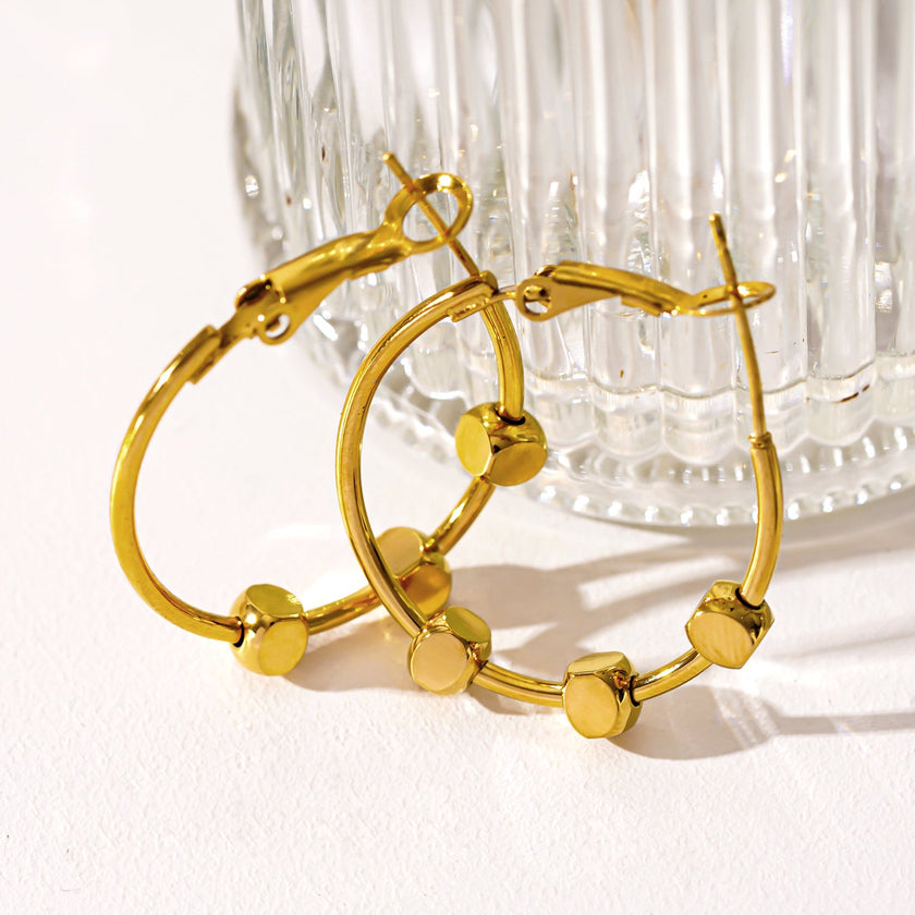 MASUYO : Boucles d'oreilles rondes avant-gardistes rehaussées d'un trio de perles carrées.