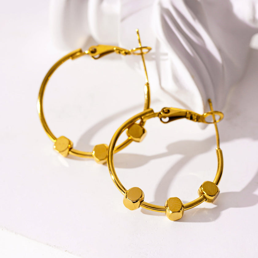 MASUYO : Boucles d'oreilles rondes avant-gardistes rehaussées d'un trio de perles carrées.