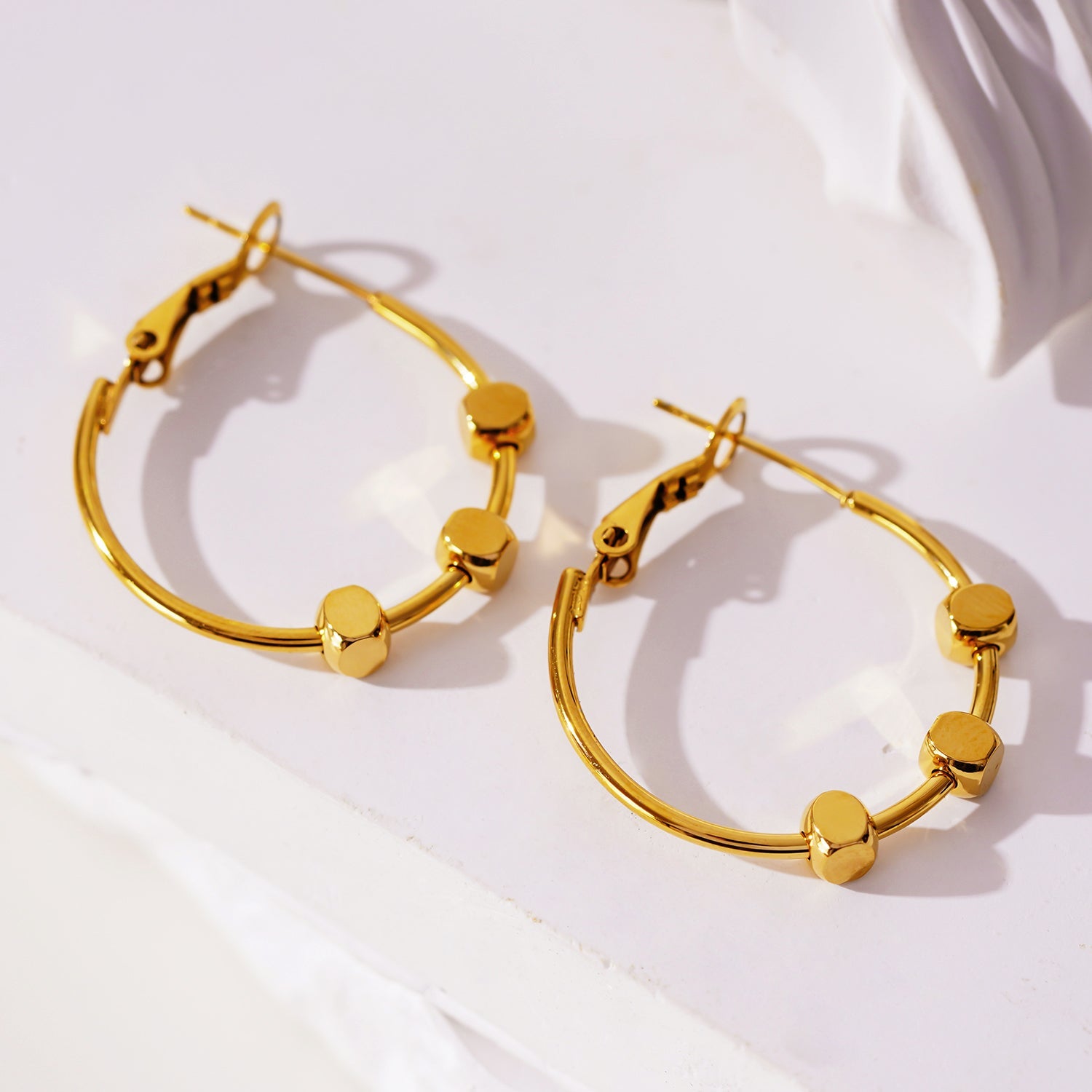 MASUYO : Boucles d'oreilles rondes avant-gardistes rehaussées d'un trio de perles carrées.