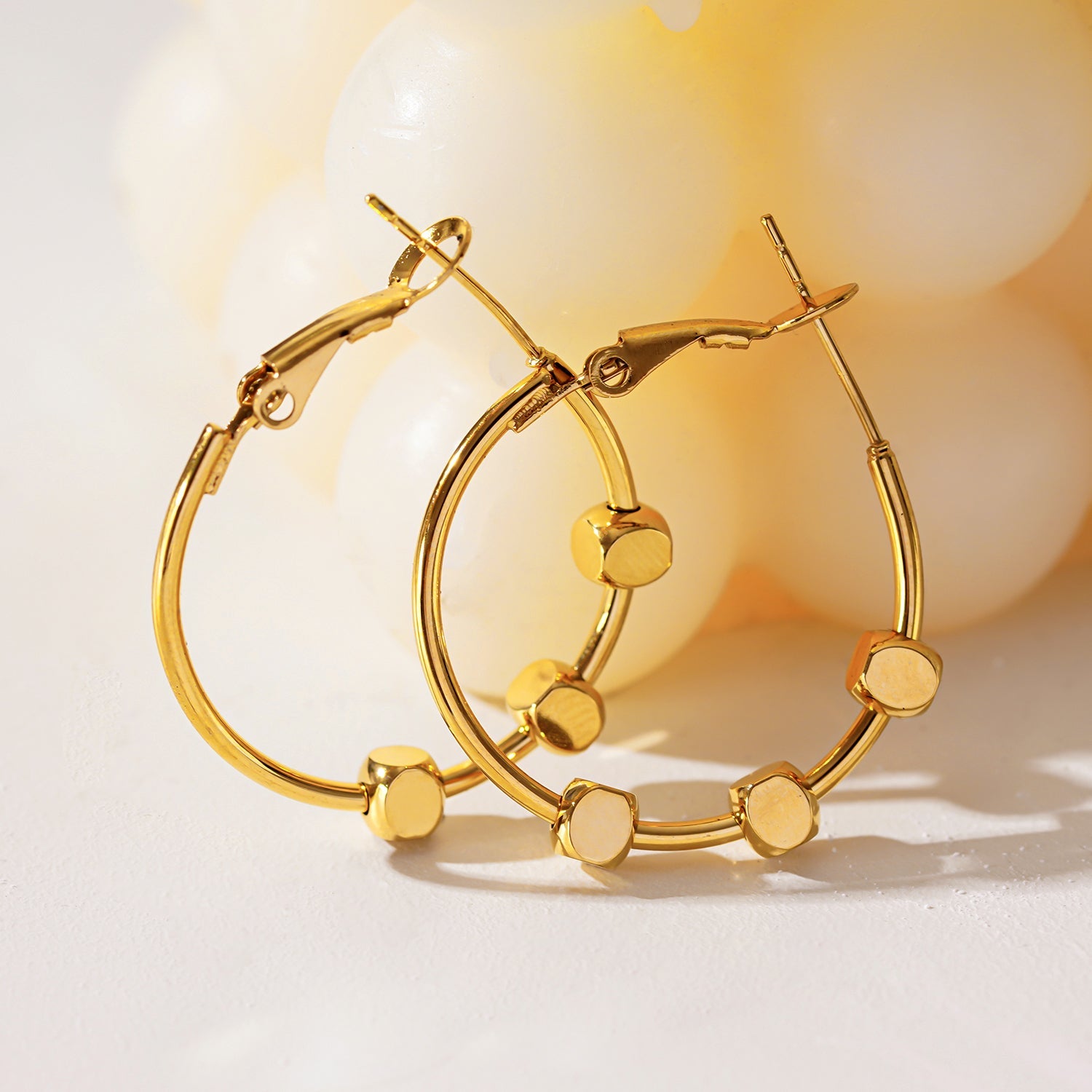 MASUYO : Boucles d'oreilles rondes avant-gardistes rehaussées d'un trio de perles carrées.