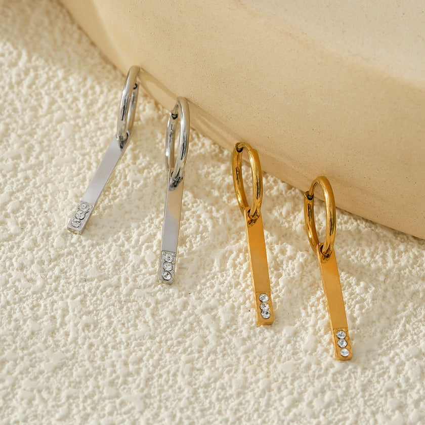 Style MAYLA : Boucles d’oreilles dorées avec un charme minimaliste mettant en valeur un trio de pierres précieuses en zircone.