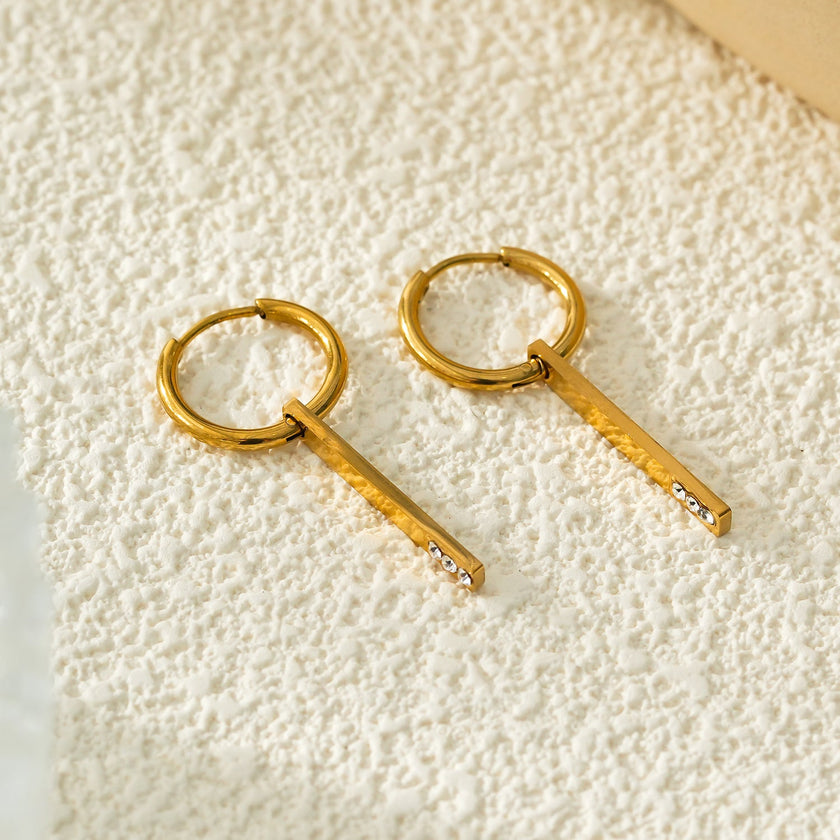 Style MAYLA : Boucles d’oreilles dorées avec un charme minimaliste mettant en valeur un trio de pierres précieuses en zircone.