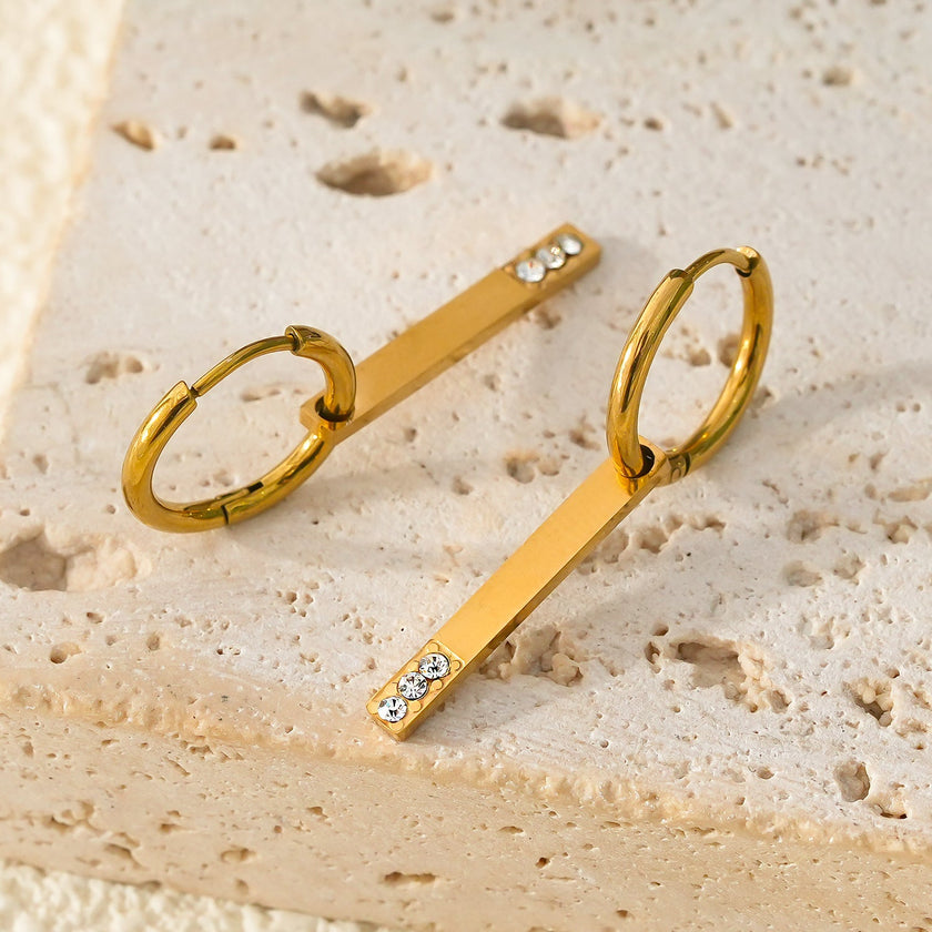Style MAYLA : Boucles d’oreilles dorées avec un charme minimaliste mettant en valeur un trio de pierres précieuses en zircone.