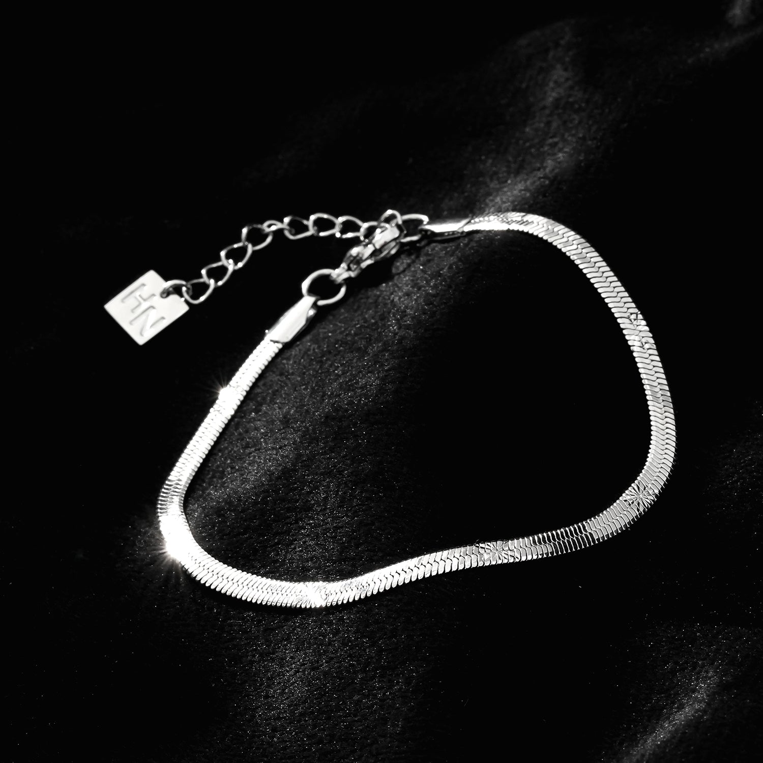 MUKER : Bracelet en chaîne argentée texturée effet peau de serpent avec motif étoile en relief.