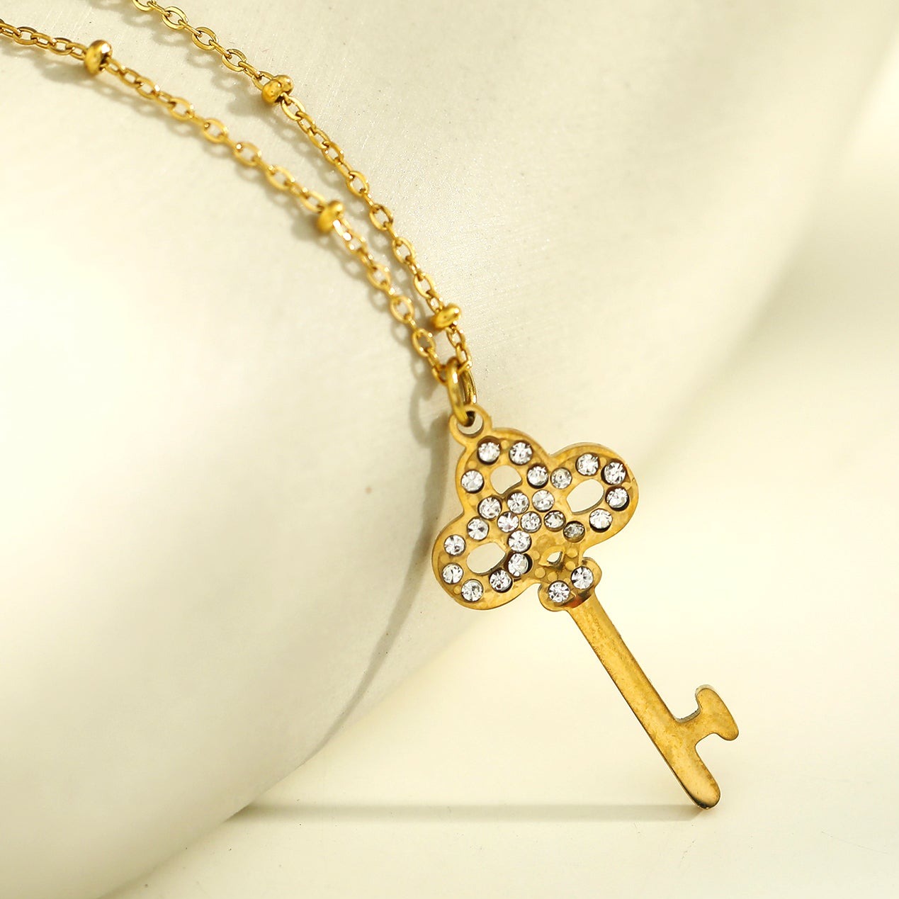Collier UNLOK en or perlé avec pendentif clé orné de zircons.