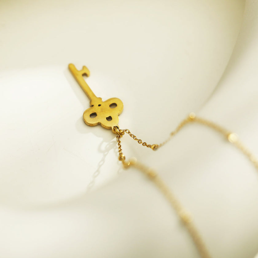 Collier UNLOK en or perlé avec pendentif clé orné de zircons.