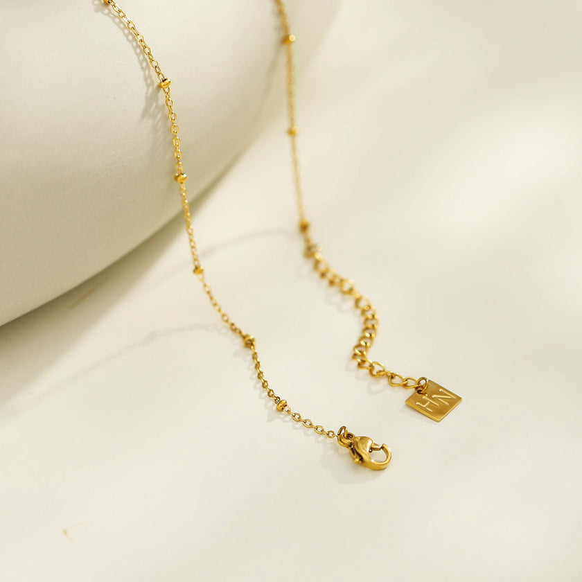 Collier UNLOK en or perlé avec pendentif clé orné de zircons.