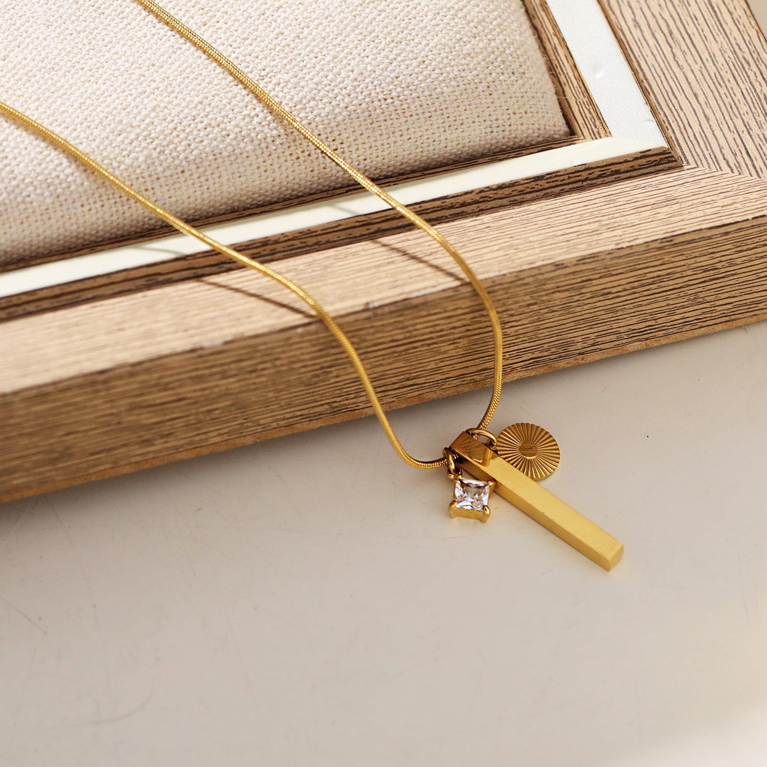 Style DEFNIE : Collier délicat à chaîne texturée effet peau de serpent, agrémenté d'un trio de breloques.