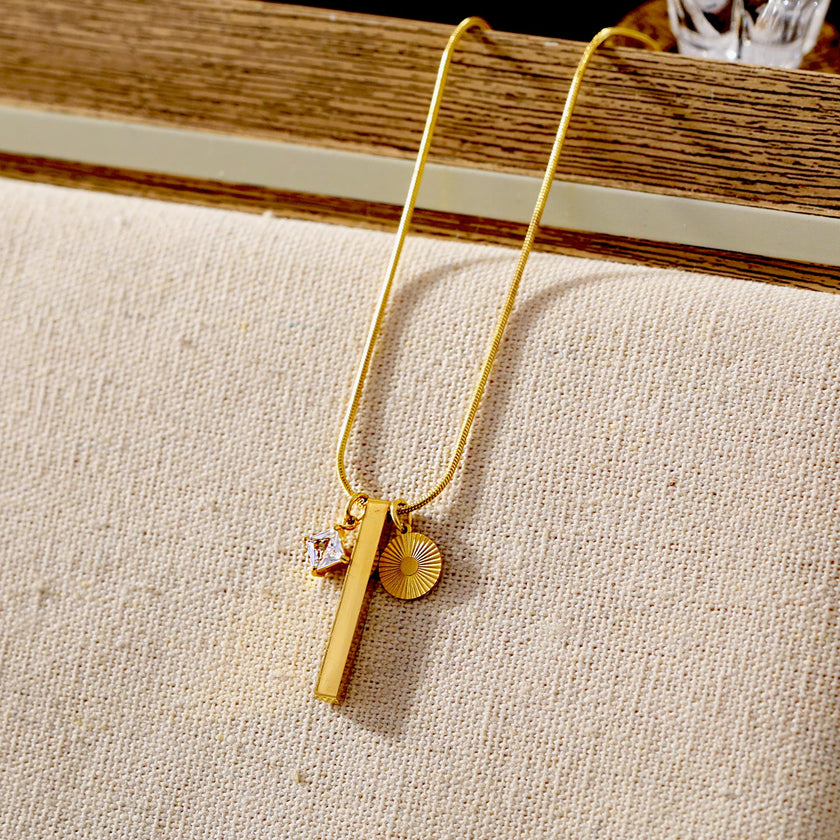 Style DEFNIE : Collier délicat à chaîne texturée effet peau de serpent, agrémenté d'un trio de breloques.