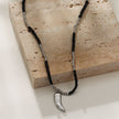 Collier RITA à chaîne perlée noir et argent avec pendentif dent en argent gravé.