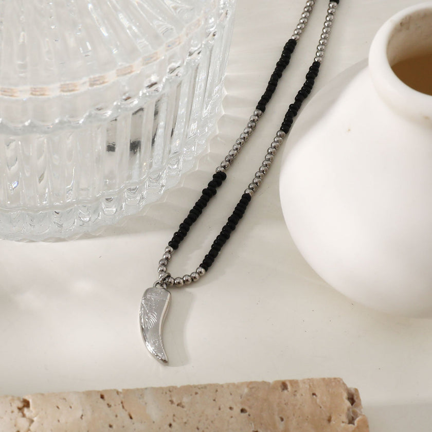 Collier RITA à chaîne perlée noir et argent avec pendentif dent en argent gravé.