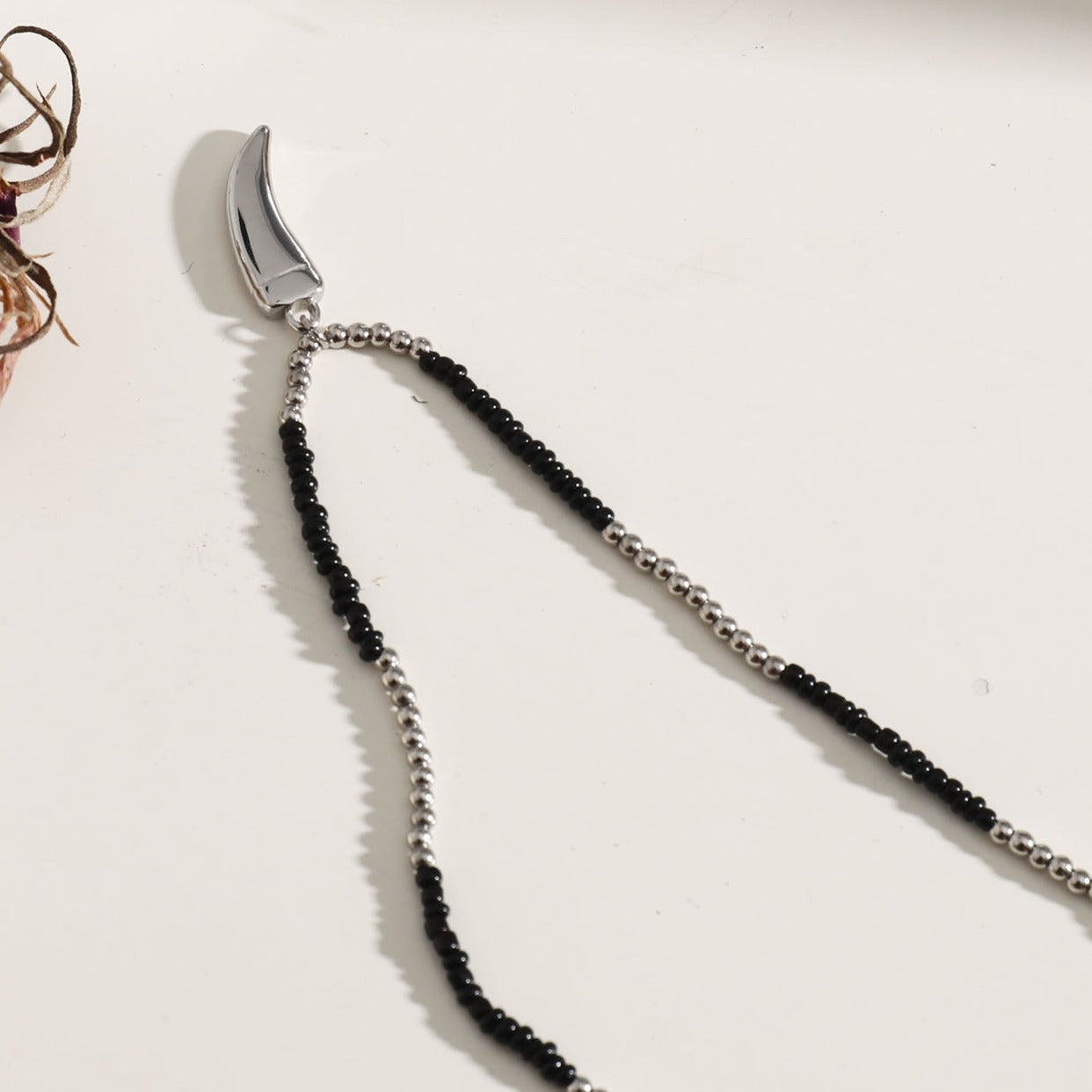 Collier RITA à chaîne perlée noir et argent avec pendentif dent en argent gravé.