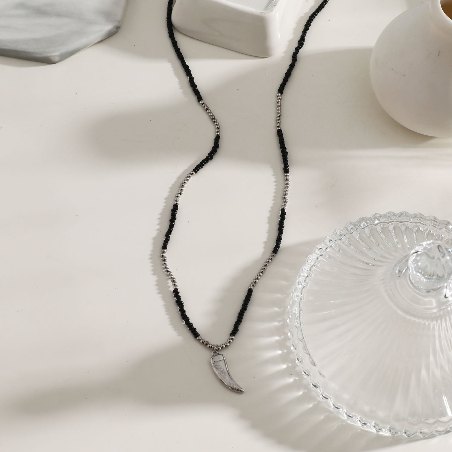 Collier RITA à chaîne perlée noir et argent avec pendentif dent en argent gravé.
