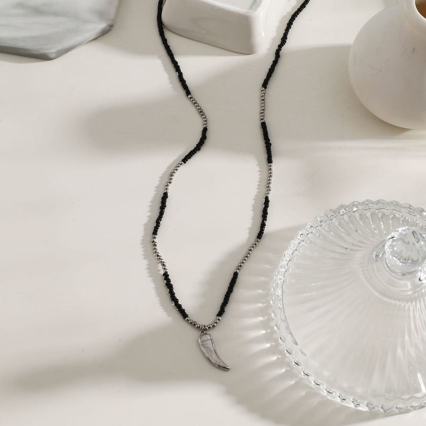 Collier RITA à chaîne perlée noir et argent avec pendentif dent en argent gravé.