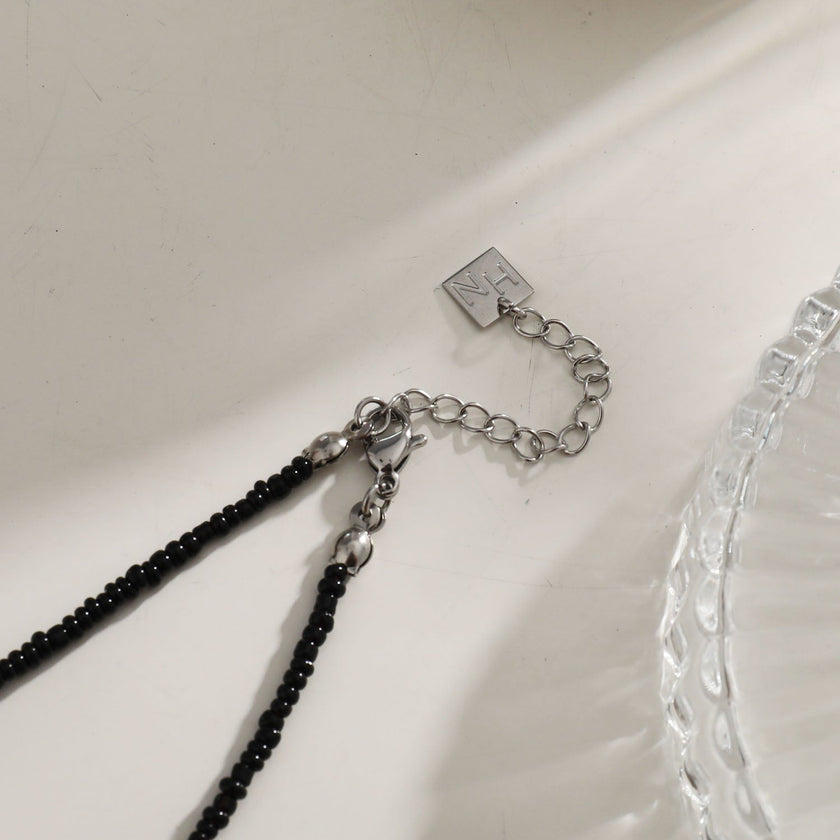 Collier RITA à chaîne perlée noir et argent avec pendentif dent en argent gravé.