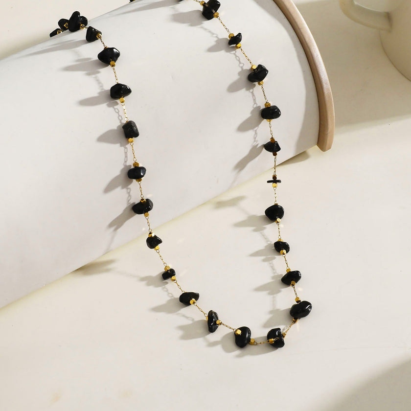 Collier SARA en perles carrées dorées miniatures et pierres naturelles noires.