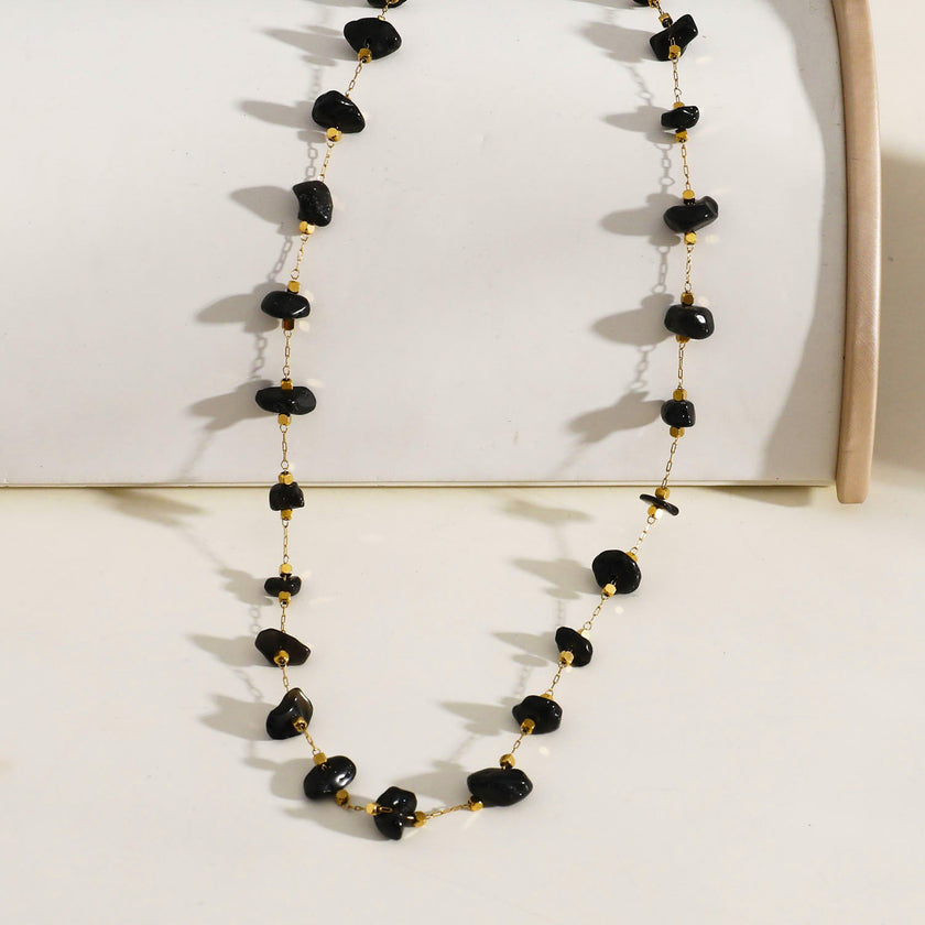 Collier SARA en perles carrées dorées miniatures et pierres naturelles noires.