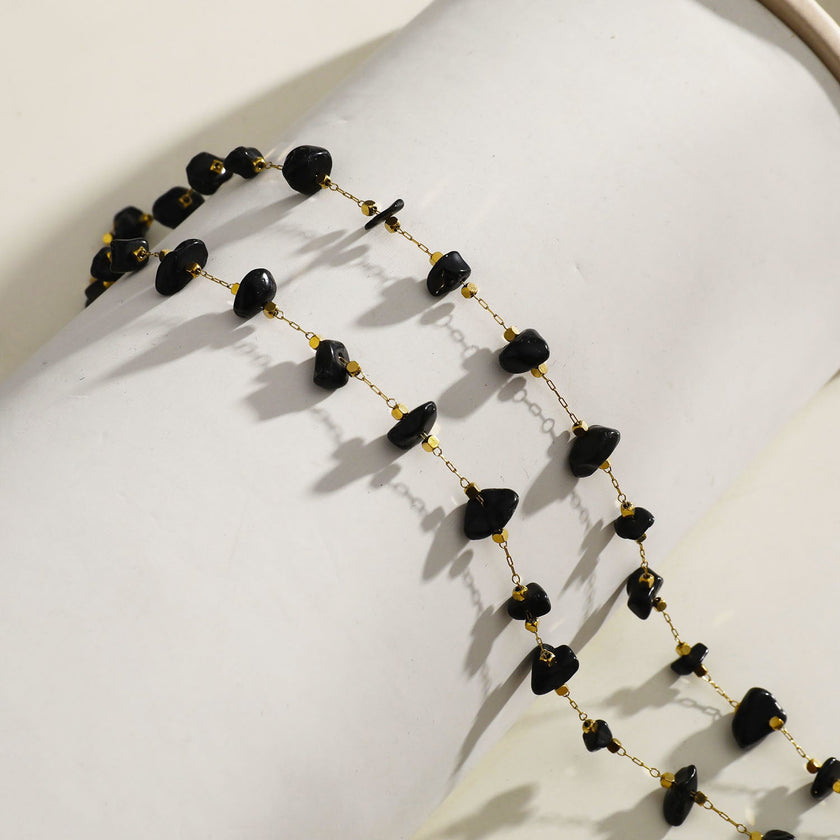 Collier SARA en perles carrées dorées miniatures et pierres naturelles noires.