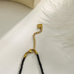 Collier RITA à chaîne perlée noir et or avec pendentif dent en or gravé.