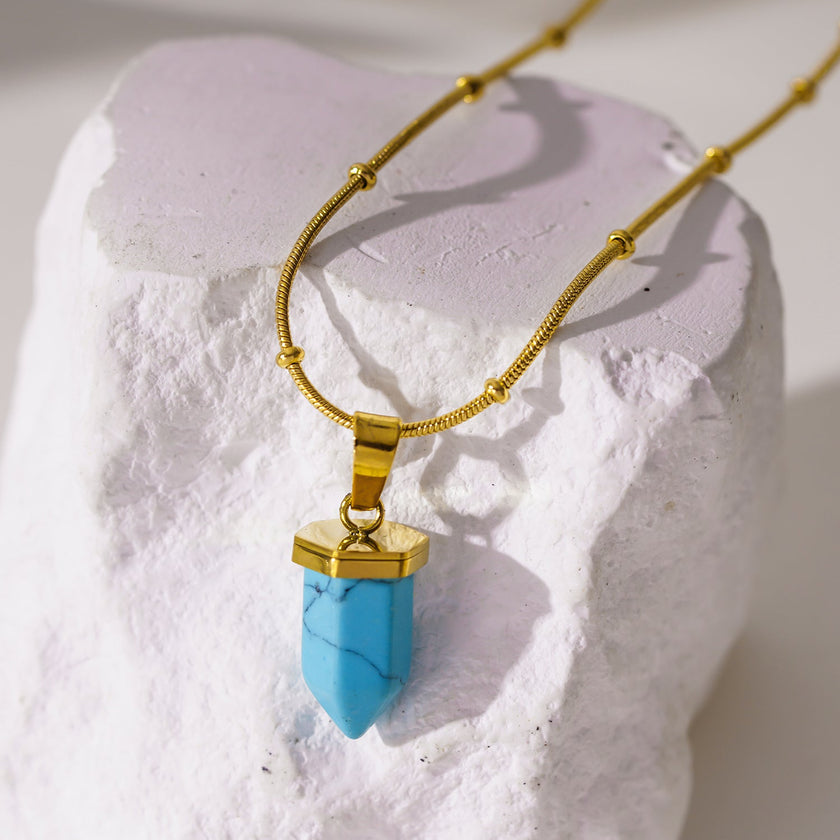 PIPPI : Collier avec pendentif en pierre turquoise africaine, suspendu à une chaîne perlée texturée imitant la peau de serpent.