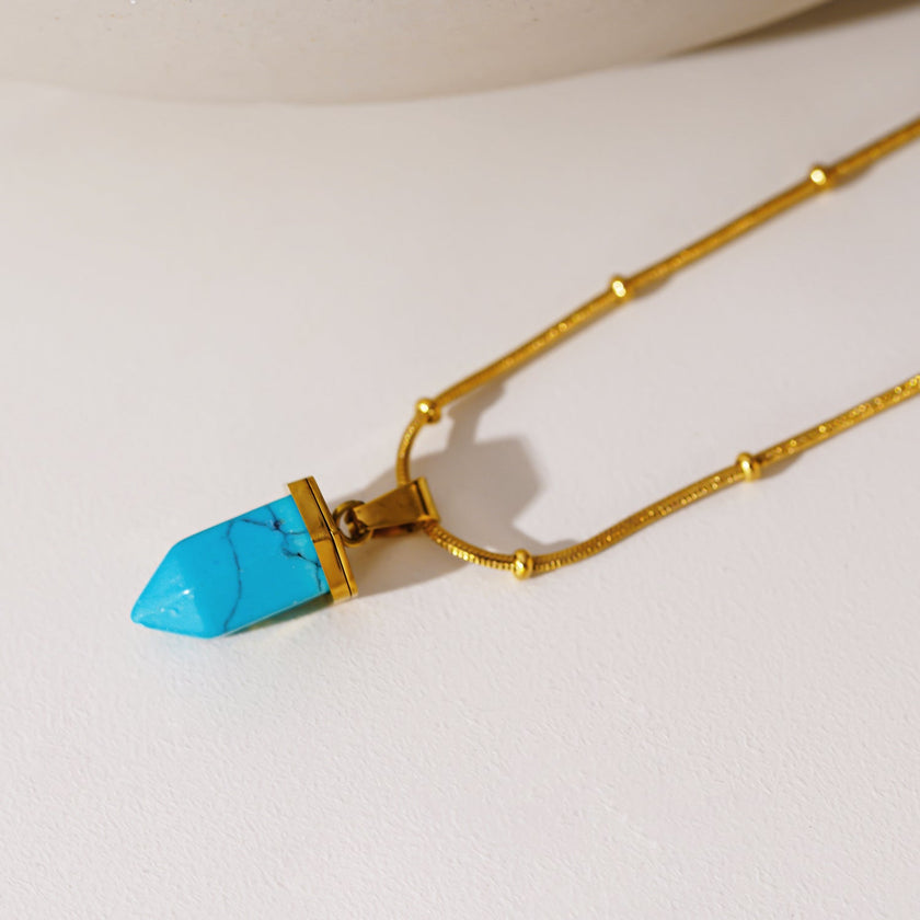 PIPPI : Collier avec pendentif en pierre turquoise africaine, suspendu à une chaîne perlée texturée imitant la peau de serpent.