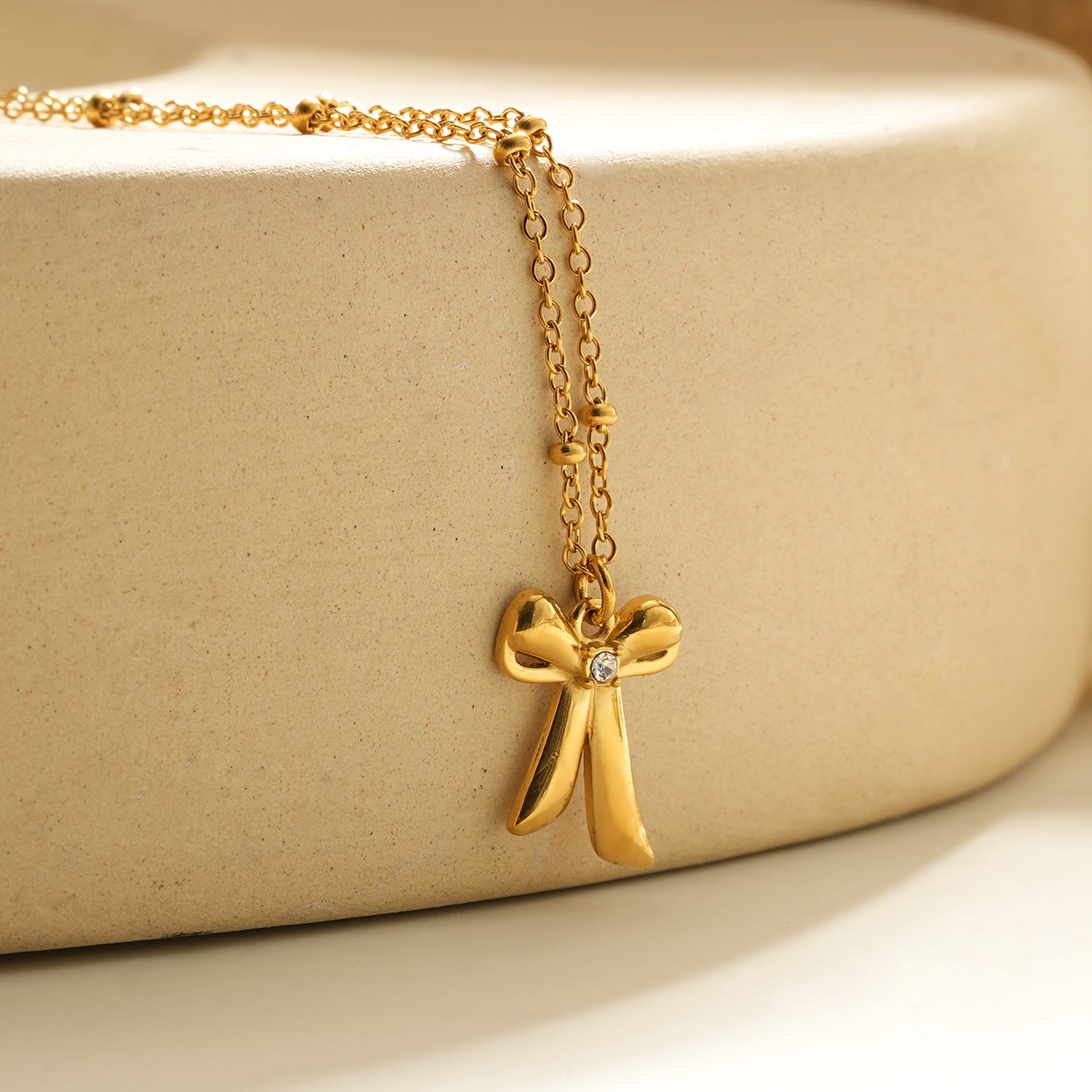 TALIANA Gold : Collier délicat à perles avec pendentif nœud et zircone solitaire – Bijou élégant pour tous les jours