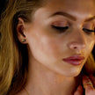 TINDRA : Boucles d'oreilles en forme d'ovale en or avec un zircon solitaire.