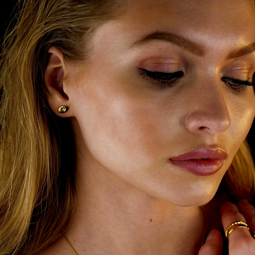 TINDRA : Boucles d'oreilles en forme d'ovale en or avec un zircon solitaire.